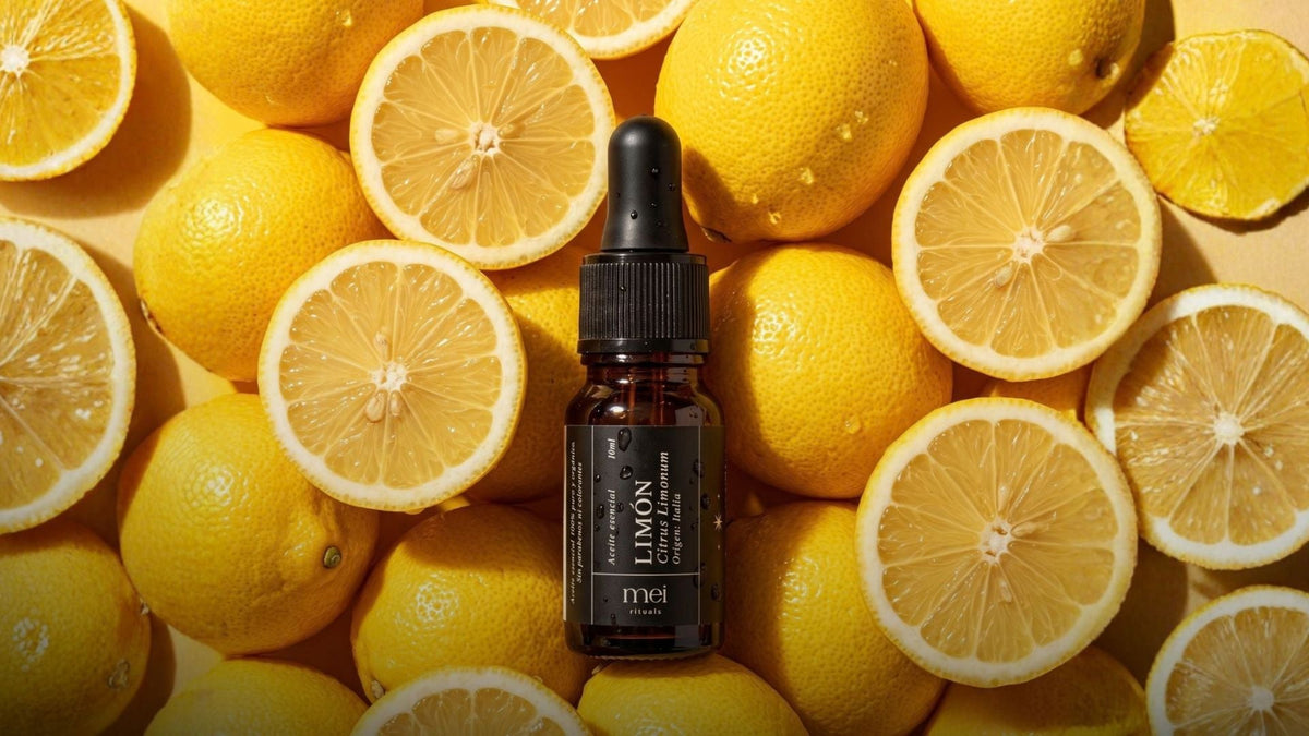 Aceite esencial de limón de Mei Rituals en frasco ámbar con gotero entre limones frescos, guía de aceites esenciales de origen único